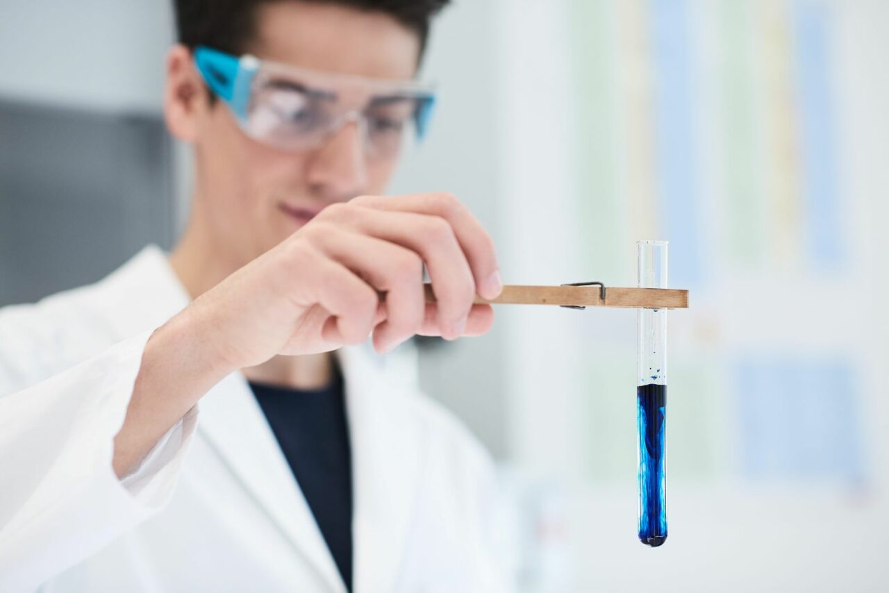 mann hält reagenzglas mit blauer flüssigkeit