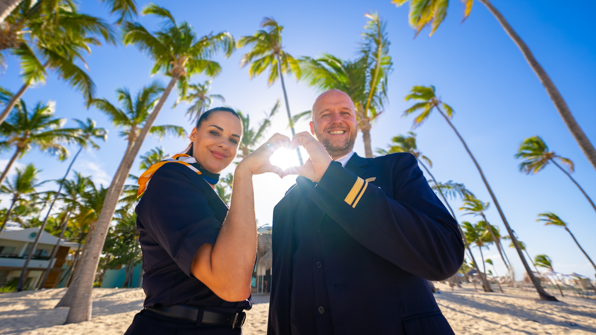 mann und frau in uniform vor palmen an einem strand