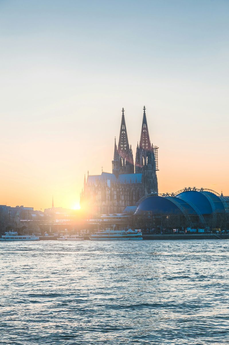 Kölner Dom mit dem Rhein im Vordergrund im Sonnenlicht