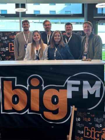 Mitarbeitende von Audiotainment Südwest hinter einer Theke mit bigFM-Logo