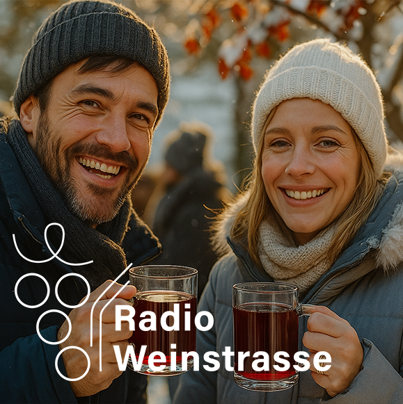 Ein dunkelhaariger Mann mit Bart und schwarzer Mütze trinkt mit einer Frau mit langen Haaren und weißer Mütze Glühwein auf einem Weihnachtsmarkt