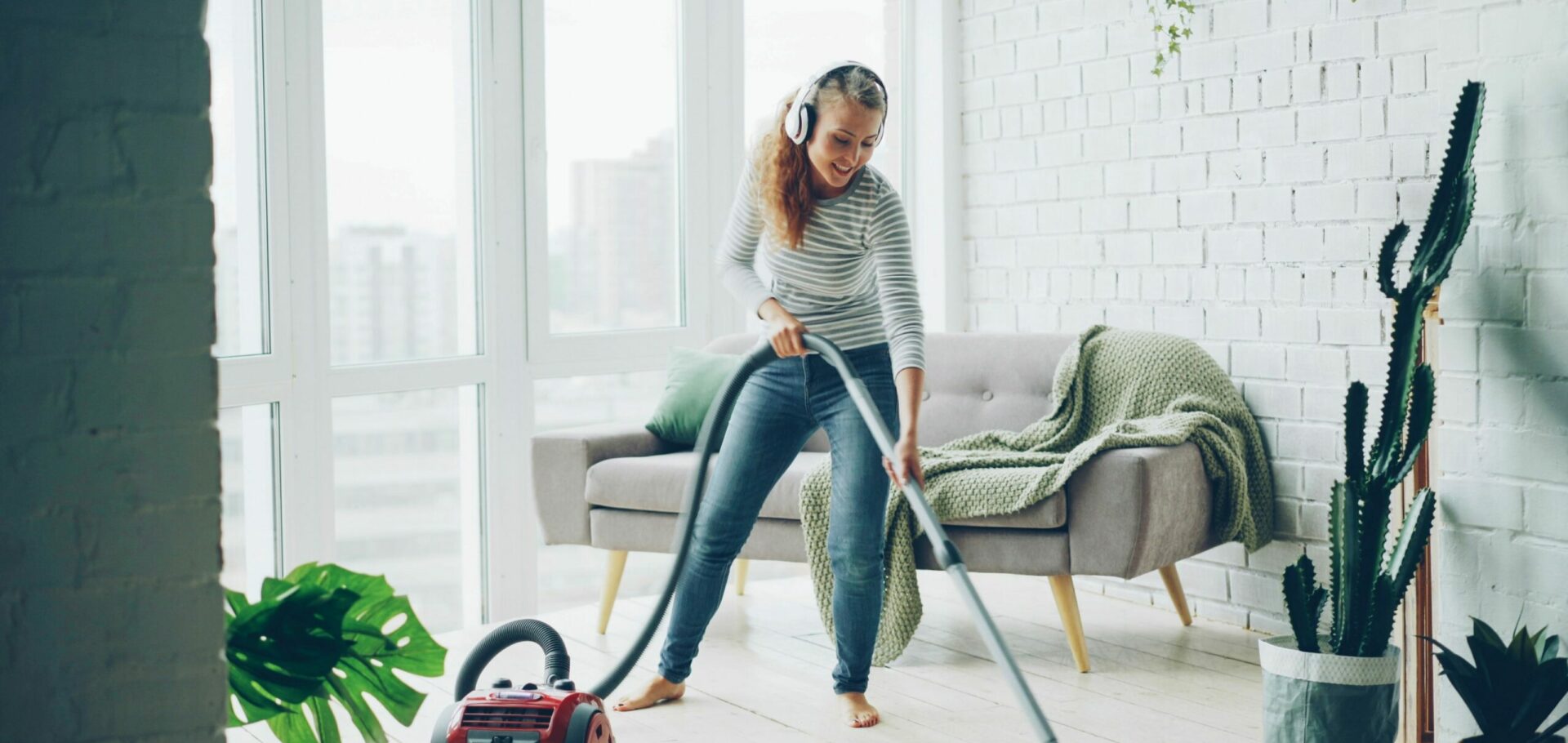 frau mit kopfhörern, die staubsaugt und fröhlich ist